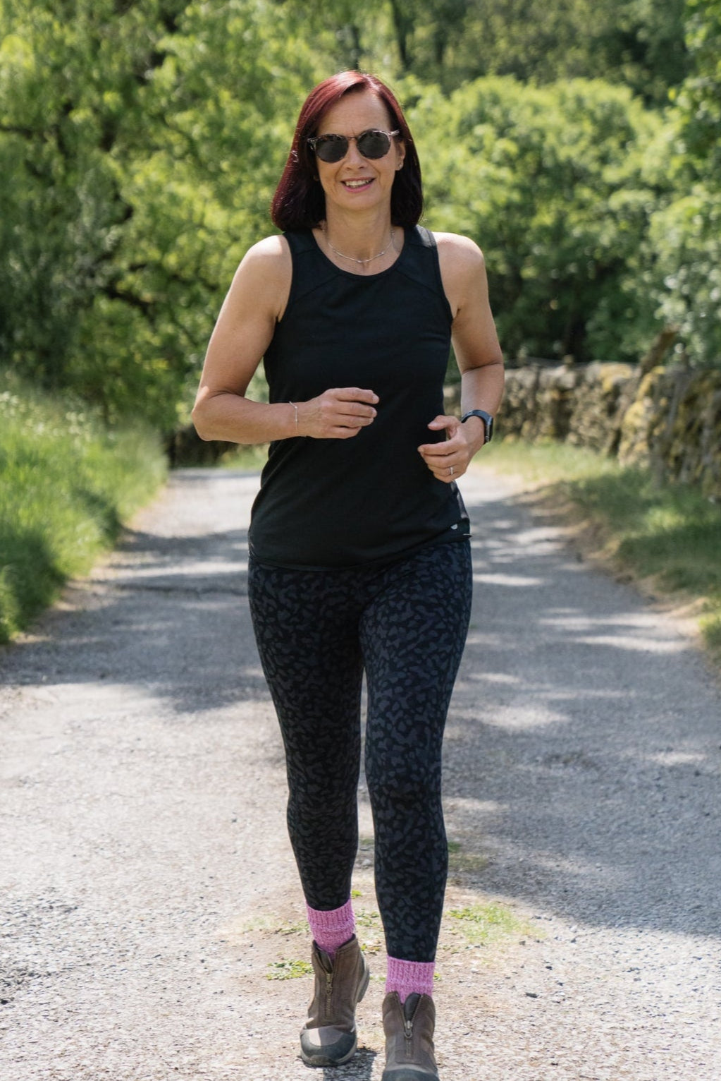 Woman running on a path surrounded by greenery