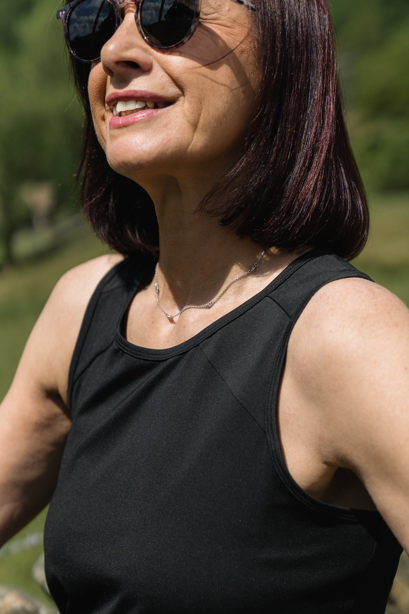 Woman wearing sunglasses and a black tank top outdoors