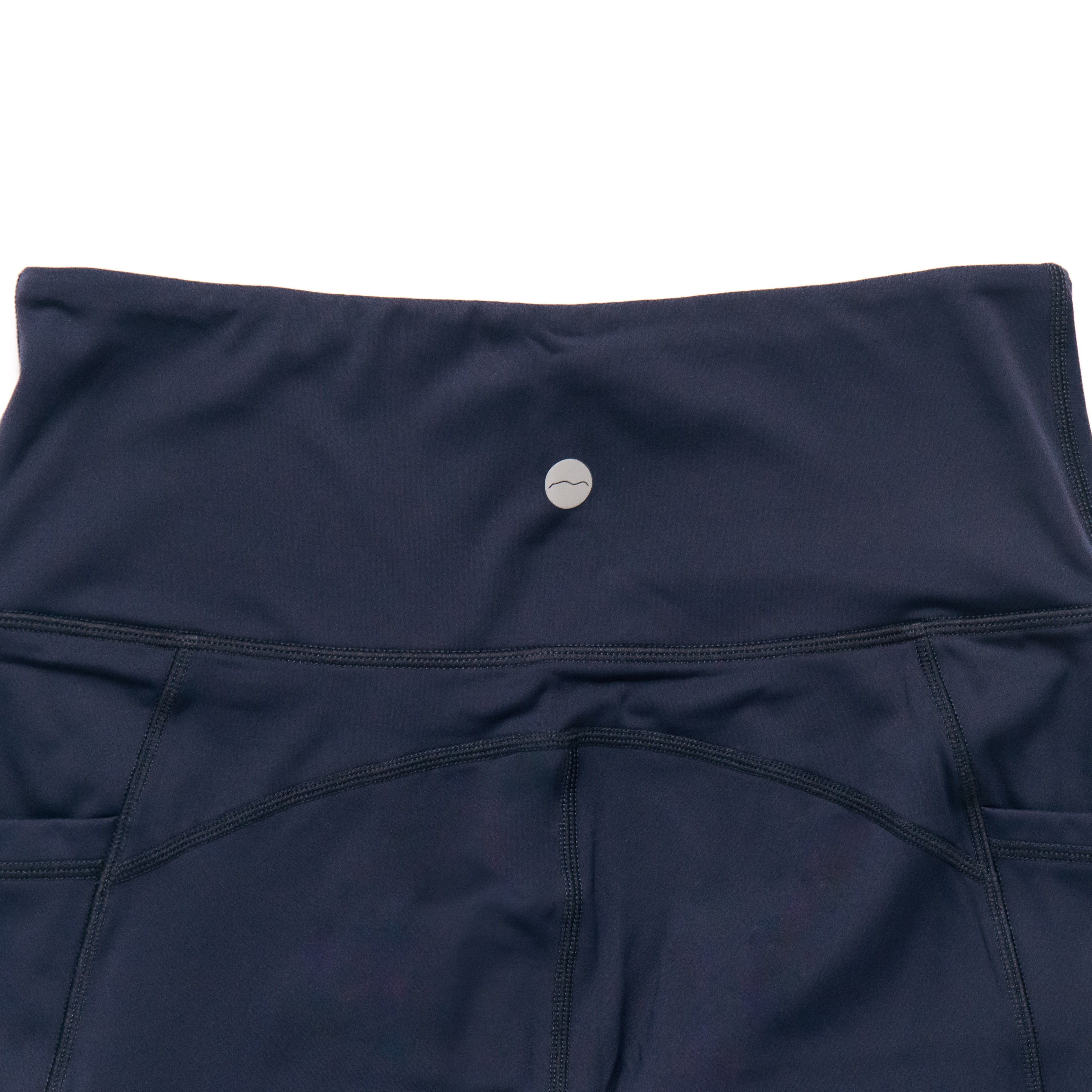 Navy blue capri leggings with a badge on a white background