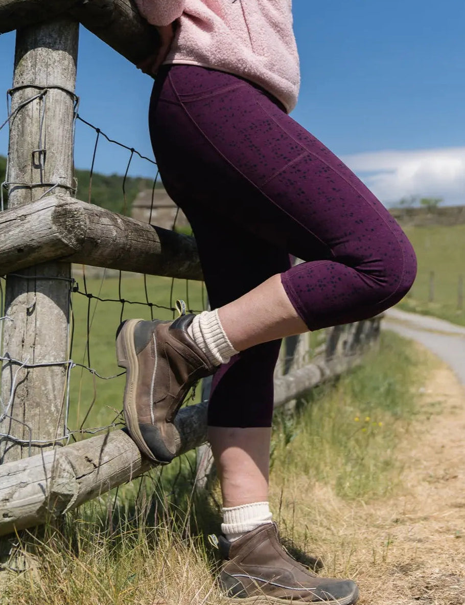 Person sitting on a wooden fence by a rural road with a clear blue sky.