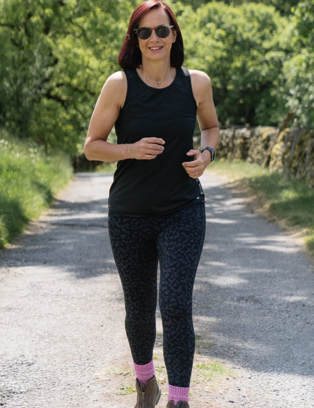 Woman running on a path surrounded by greenery