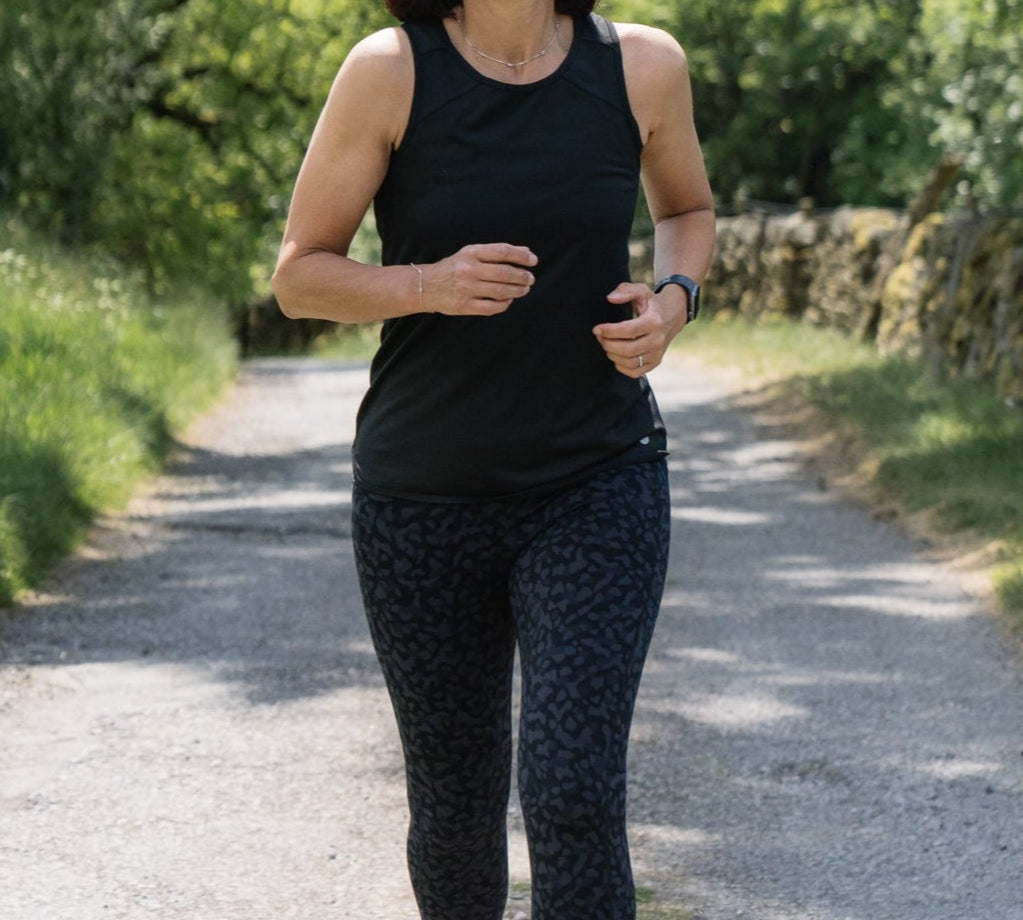Woman running on a path surrounded by greenery