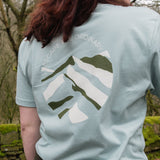 Person wearing a light blue t-shirt with a design outdoors