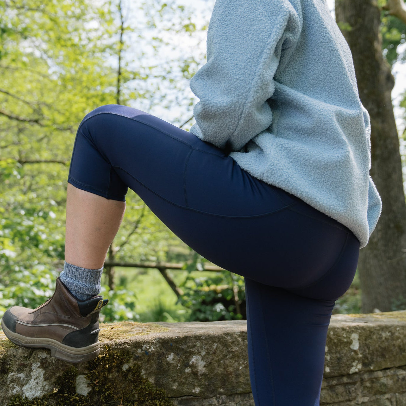 Person sitting on a stone wall in a forest