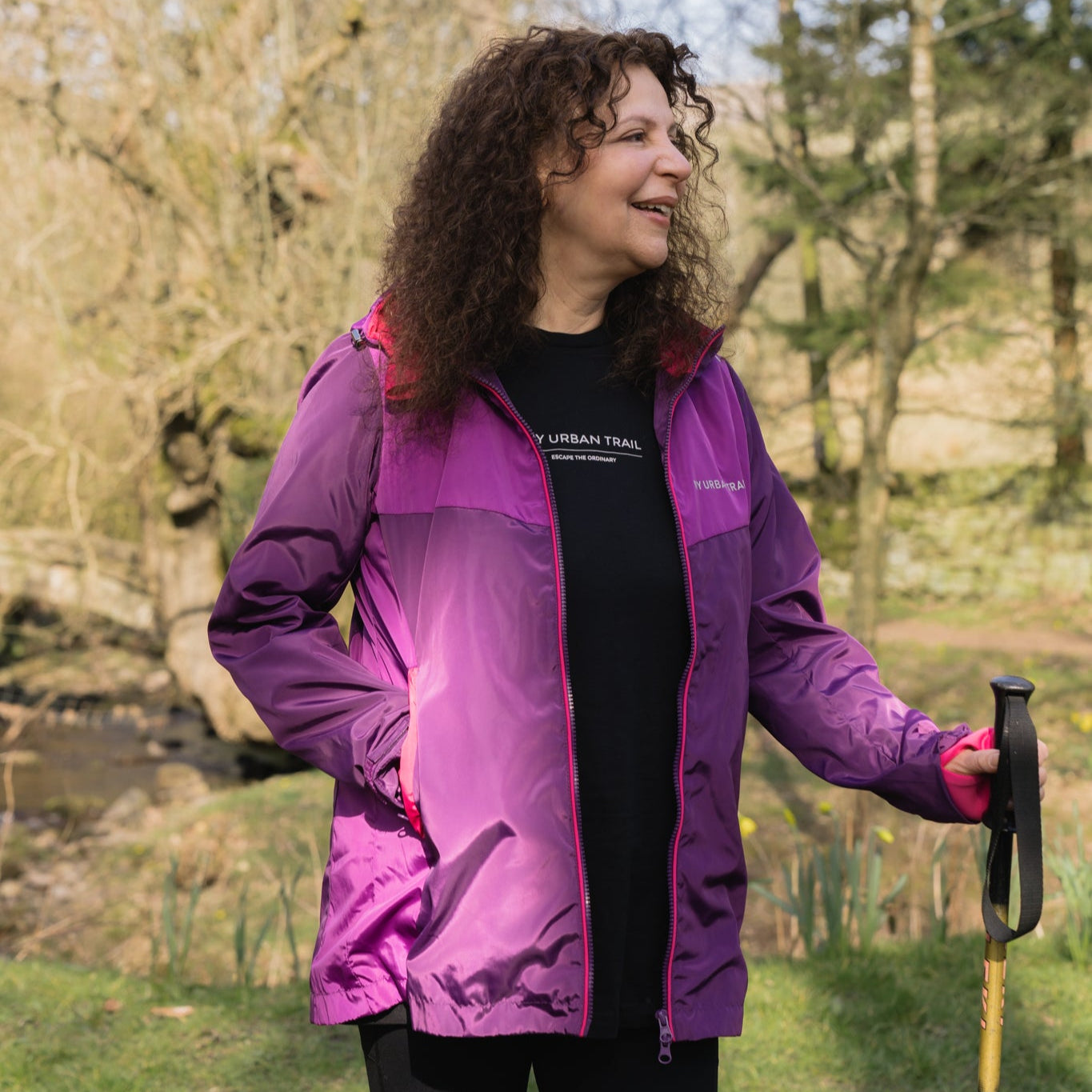 woman wearing purple waterproof and walking pole