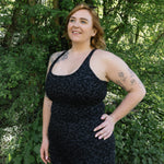 Woman wearing a black dress standing in a forested area